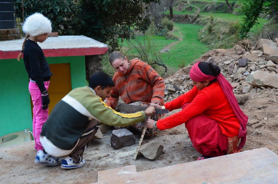 A volunteer and community members building a compost toilet.